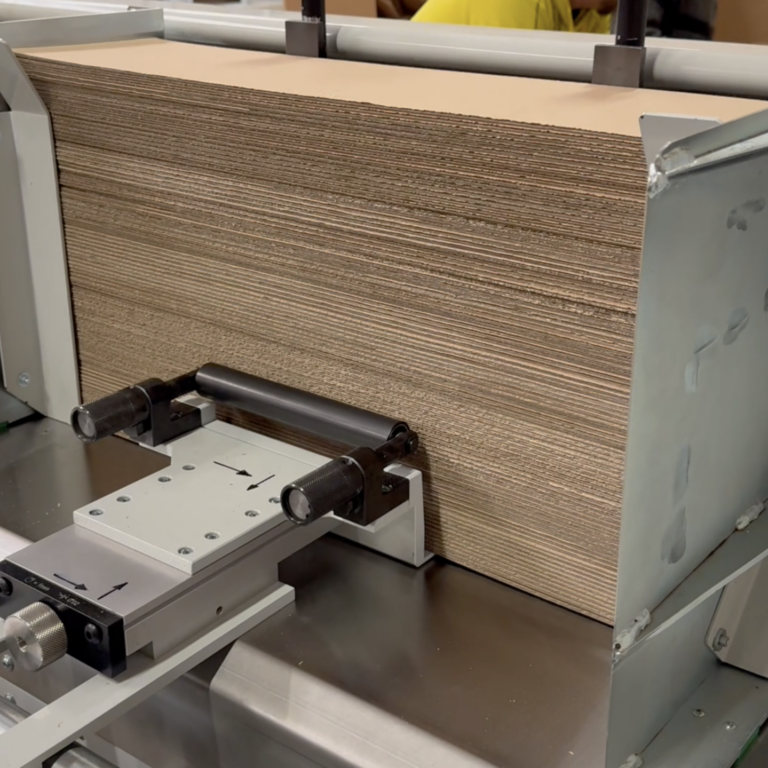 Schneidemaschine Kolibri – Präzise Ausrichtung von Wellpappstapeln Stapel aus Wellpappe wird in einer industriellen Schneidemaschine seitlich ausgerichtet und fixiert.