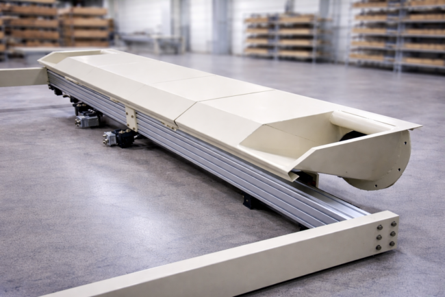 Industrielle Maschine zur Herstellung von Wabenplatten aus Papier mit Schutzabdeckung und Führungsschiene in einer Produktionshalle.