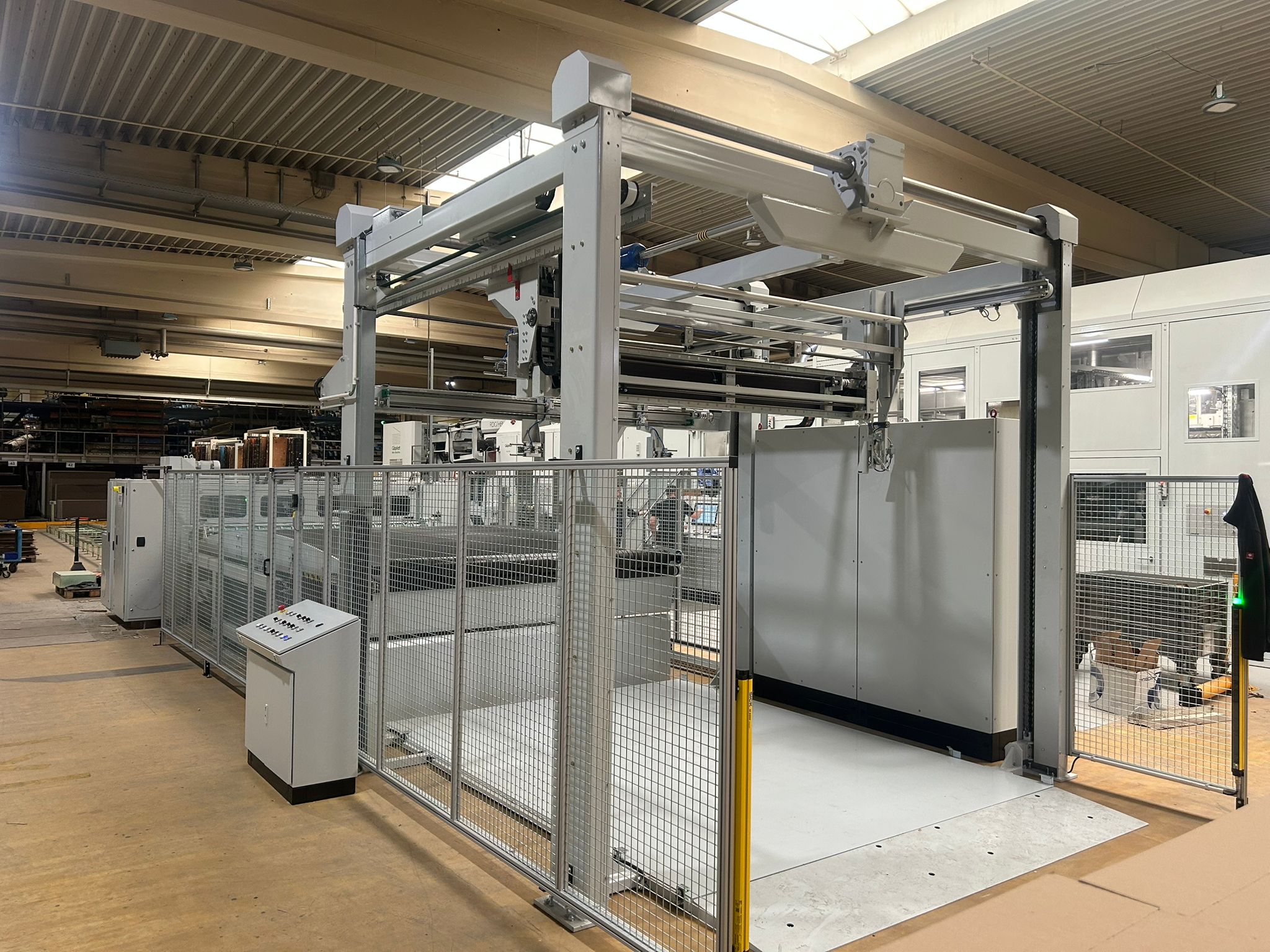Seitliche Ansicht der Schneidanlage mit Förderbereich und Schutzgitter in industrieller Umgebung.