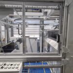 Innenansicht der Kolibri Schneidemaschine mit Steuerpult und Blick auf den automatisierten Arbeitsbereich hinter einer Schutzverglasung