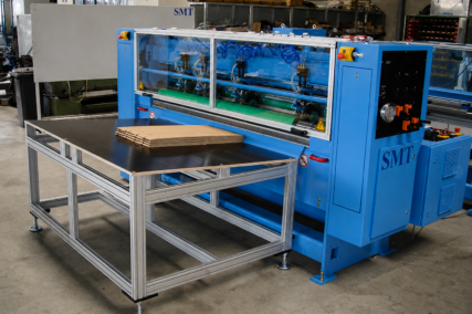 Gesamtansicht der CDS-ECO Schneidemaschine von SMT mit integriertem Zuführtisch und aufgelegtem Wellpappenstapel in einer industriellen Produktionsumgebung