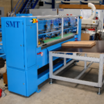 Gesamtansicht der CDS-ECO Schneidemaschine von SMT mit integriertem Zuführtisch und aufgelegtem Wellpappenstapel in einer industriellen Produktionsumgebung