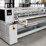 Gesamtansicht der CDS-ECO Schneidemaschine von SMT mit integriertem Zuführtisch und aufgelegtem Wellpappenstapel in einer industriellen Produktionsumgebung