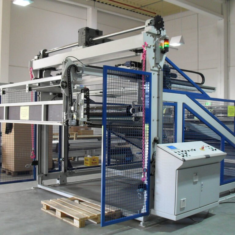 Upstacker Anlage mit Schutzumhausung Gesamtansicht einer Upstacker Anlage zur Wabenplattenproduktion mit Schutzgitter, Rollen und Bedienpult in einer industriellen Produktionshalle